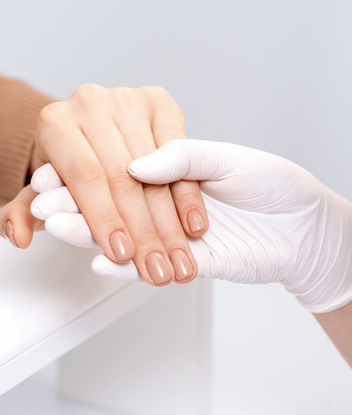 913cbbc4 manicurist hand is holding woman hand with beige manicure close up 1 min.jpg
